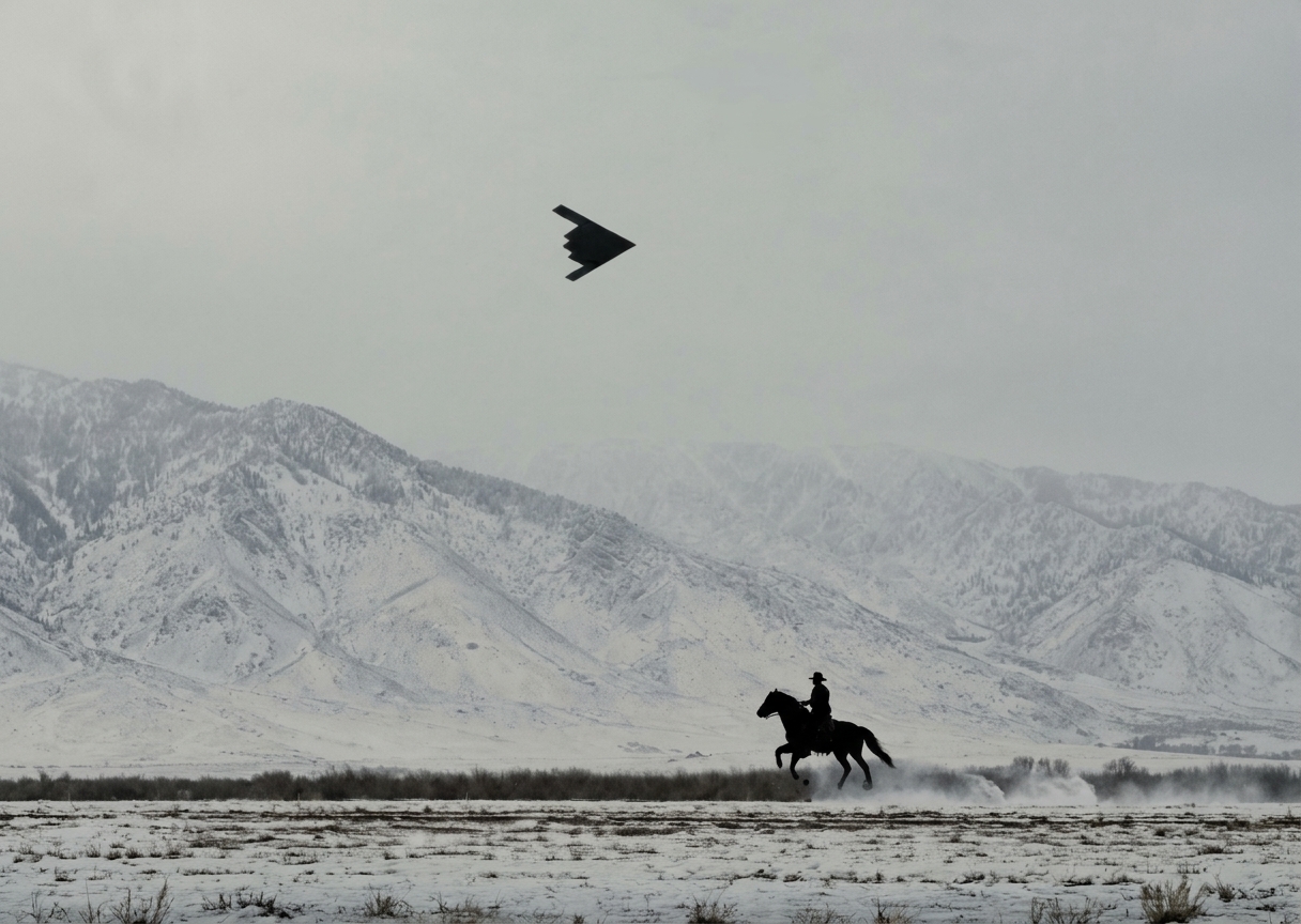 A rider crossing a snowy landscape beneath a stealth aircraft